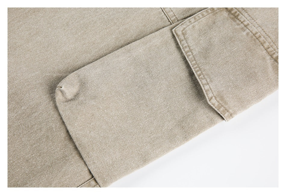 Close-up of beige pants showing a stitched flap pocket and fabric texture.