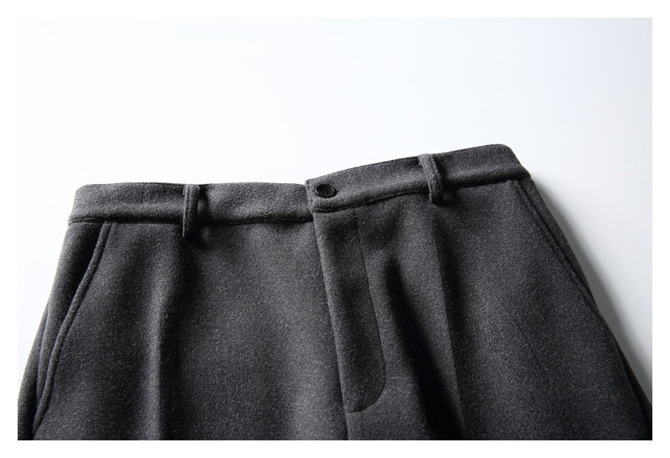 Close-up of charcoal trousers’ front waistband, belt loops, button, fly and slanted pockets.