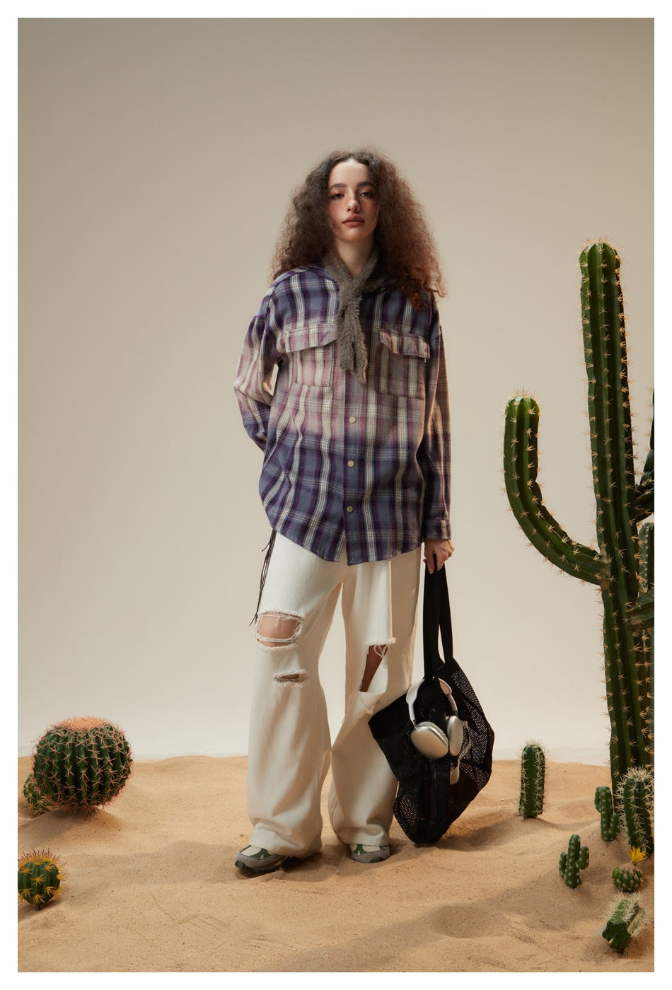 Model wearing purple plaid hooded shirt jacket over white ripped wide-leg jeans in a desert cactus set