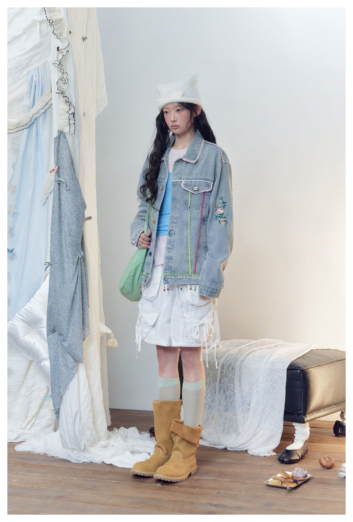 Model wearing the embroidered blue denim jacket, three-quarter view showing sleeve embroidery and beaded hem