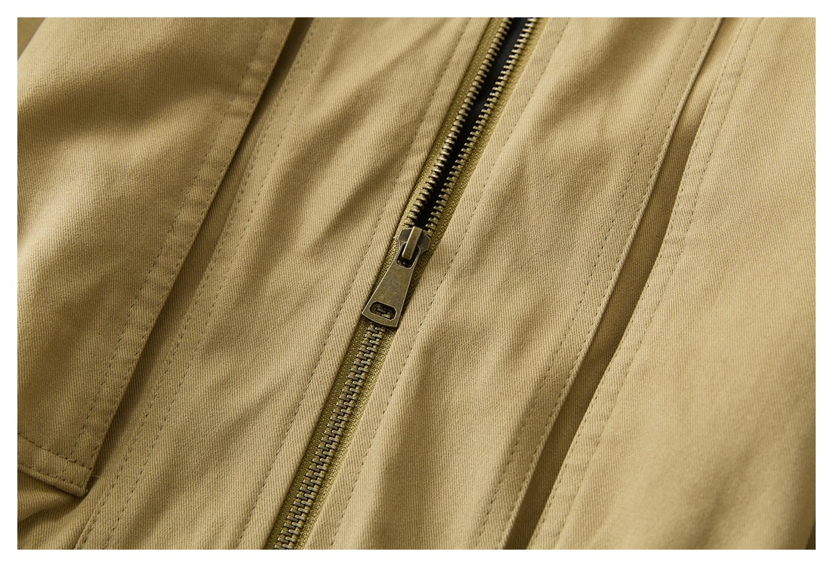 Close-up of a brass-colored zipper and stitched seams on tan fabric.