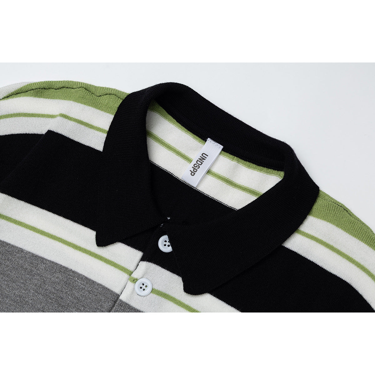Close-up of the polo's black collar, white buttons, and black, gray, white, and green stripe pattern.