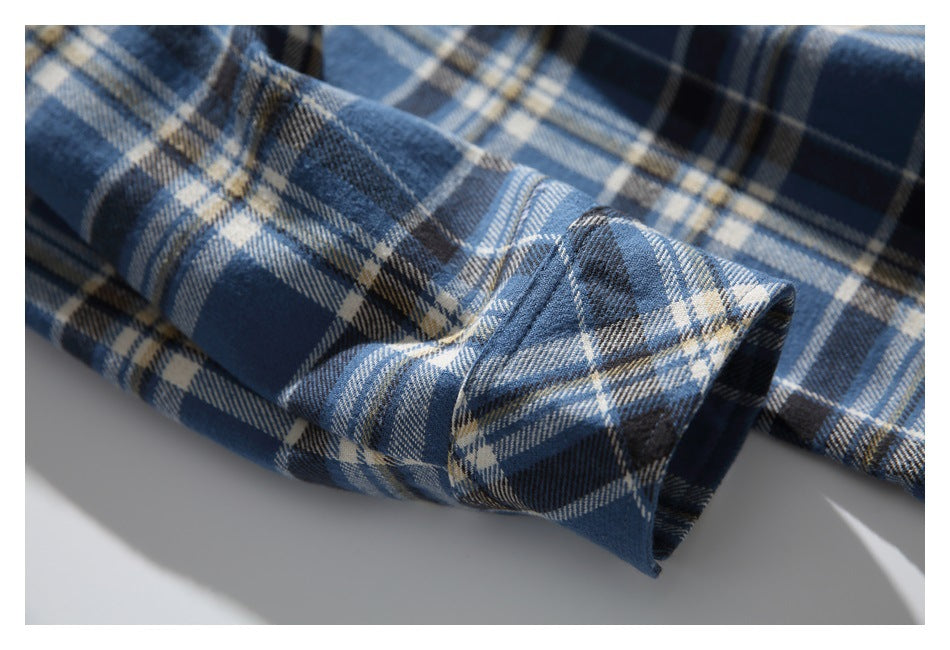 Close-up of the buttoned cuff of a blue and cream plaid shirt.