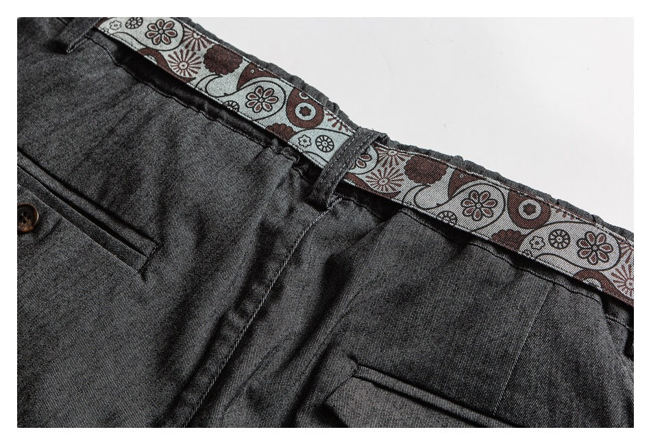Close-up of charcoal trousers showing the waistband, belt loop, pocket, and patterned inner trim.