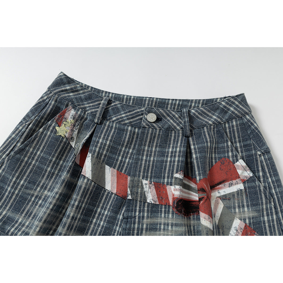 Close-up of blue-gray plaid shorts waistband and fly with a distressed red, white, and gray graphic.
