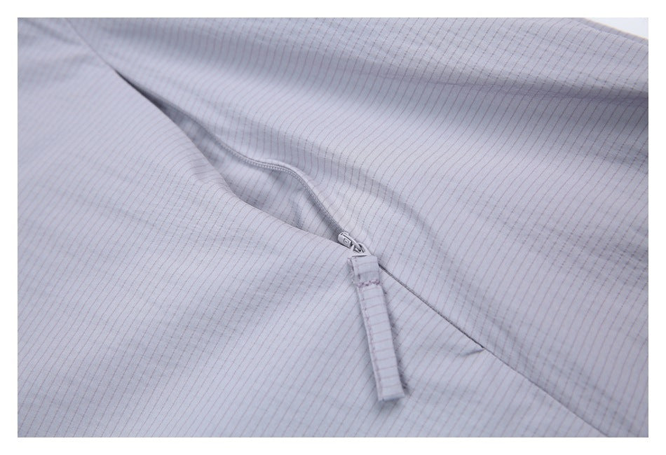 Close-up of a light gray pinstriped garment with a matching zipper and long fabric pull.