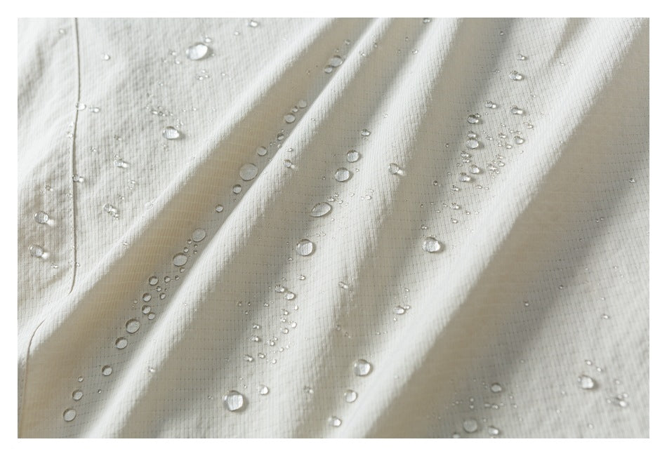 Close-up of white fabric with water droplets beading on its surface.