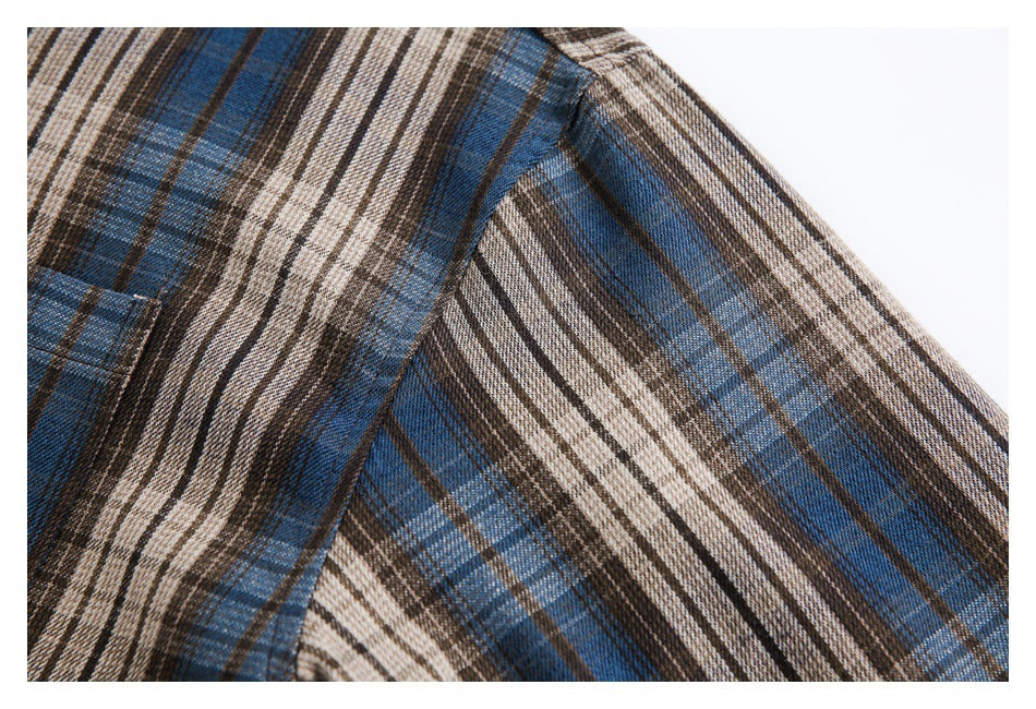 Close-up of the plaid shirt's shoulder and sleeve seam in blue, brown, and cream checks.
