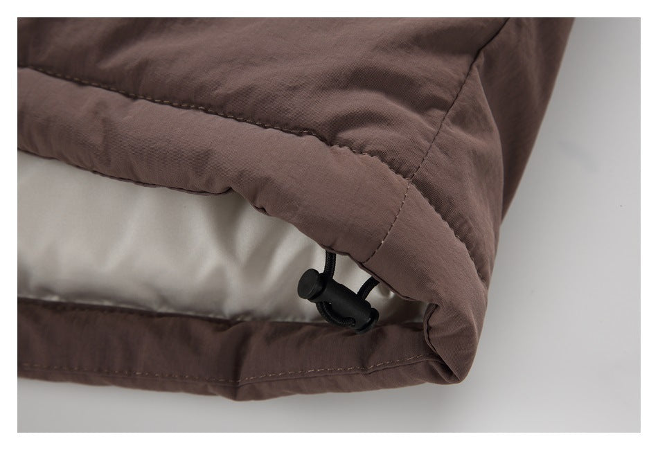 Close-up of the jacket's dark brown hem with stitching and a black adjustable drawcord stopper.