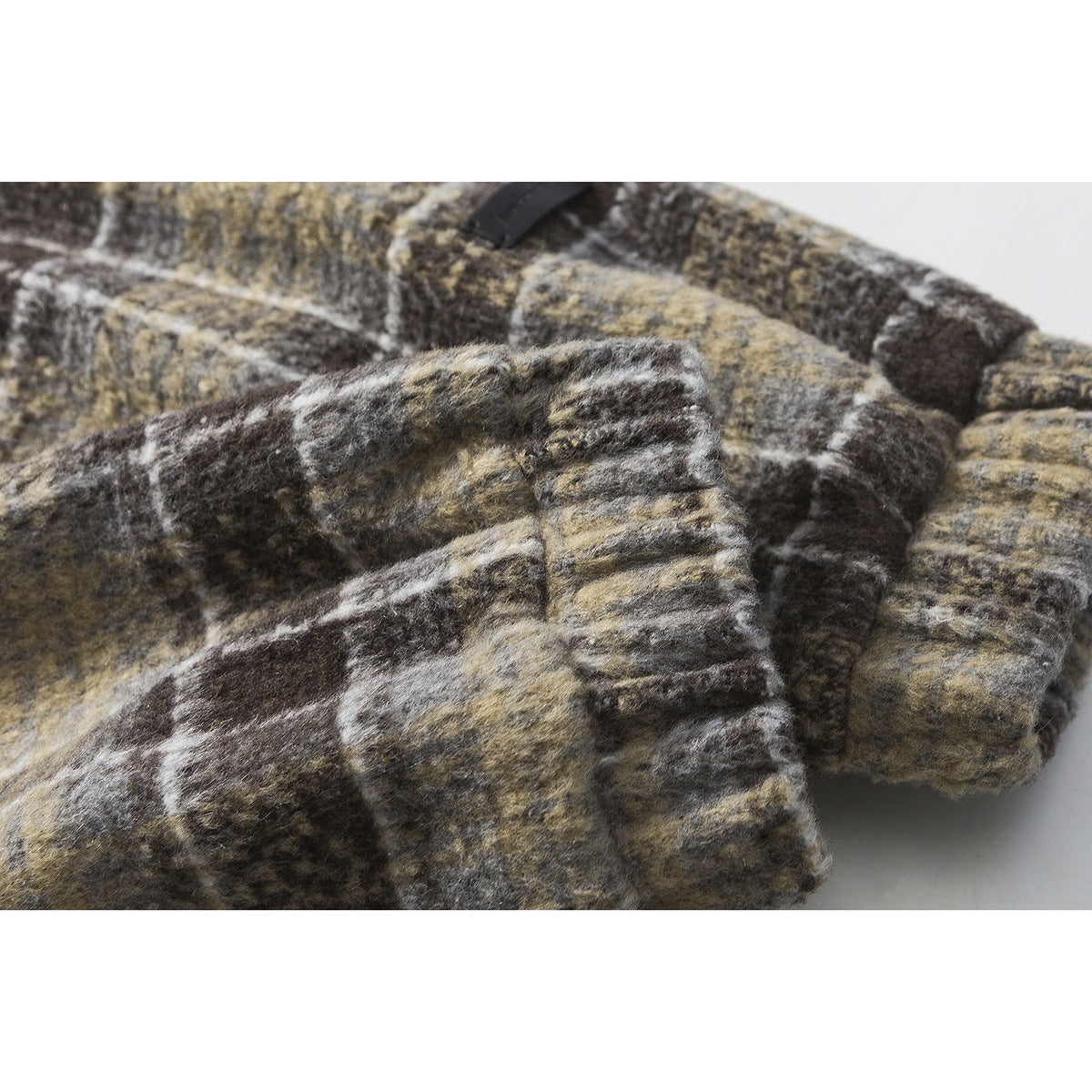 Close-up of the cuff and sleeve of a muted brown, gray, and cream plaid jacket.