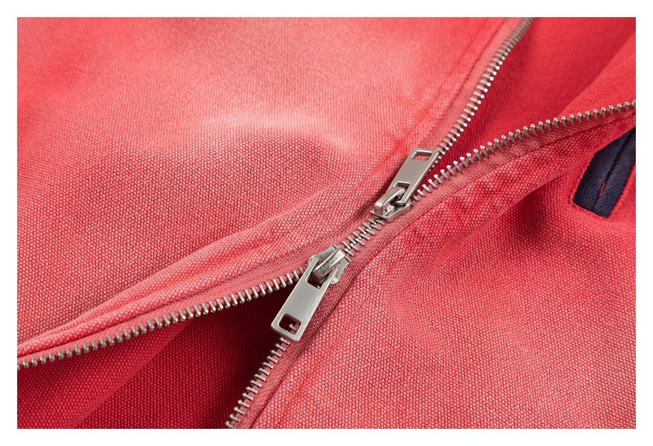 Close-up of the coral-red jacket's partially opened silver front zipper and textured fabric.