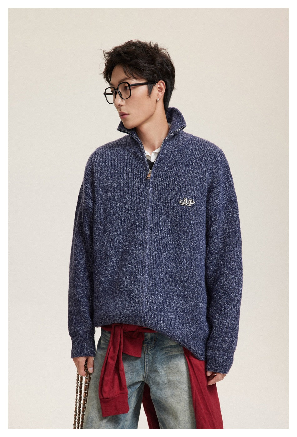 Model wearing a navy ribbed zip-neck sweater with a raised collar and chest emblem, viewed from the waist up.