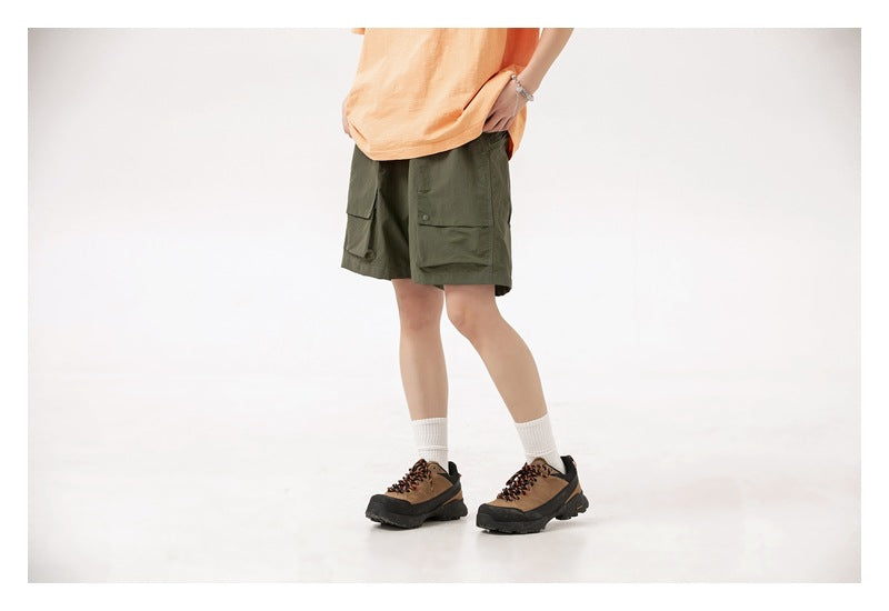 Model wearing olive green cargo shorts with large flap pockets and an orange T-shirt.