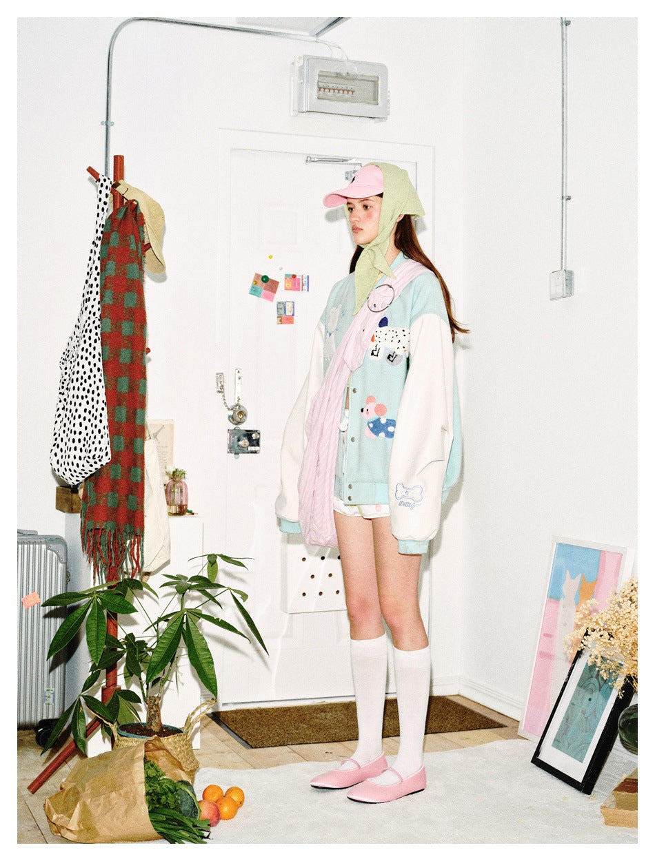Side view of a model wearing a pale aqua jacket with white sleeves and colorful appliqués.