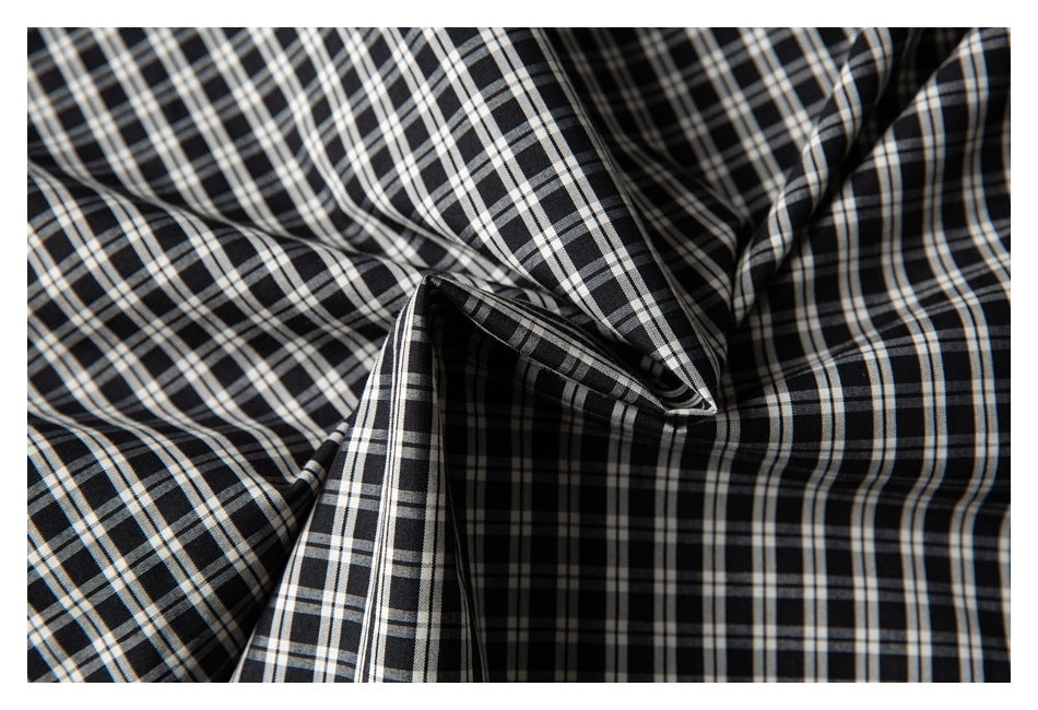 Close-up of black-and-white plaid shirt fabric gathered into soft folds.