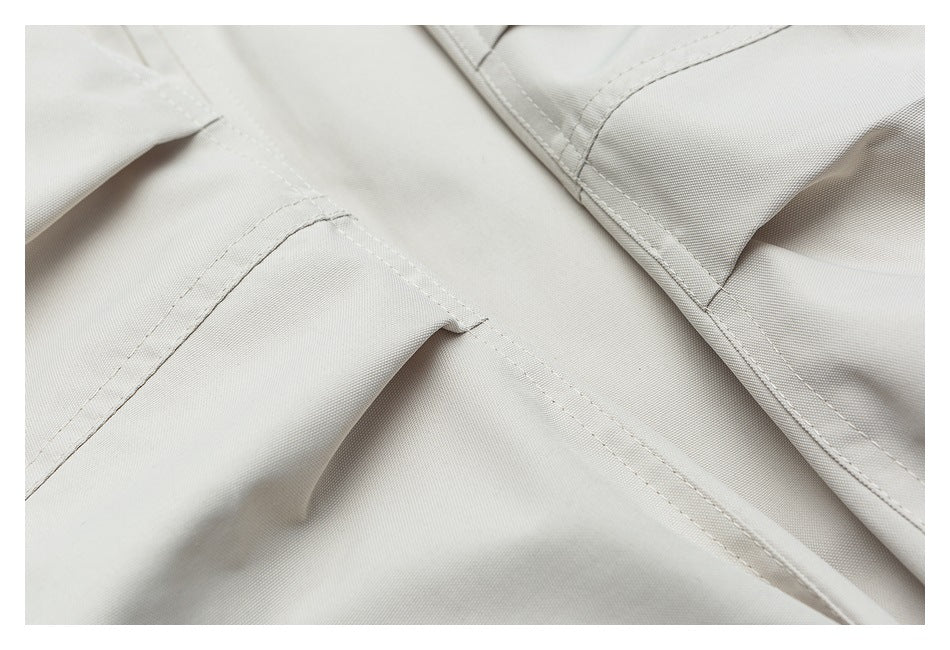 Close-up of stitched seams and a pocket opening on light beige garment fabric.