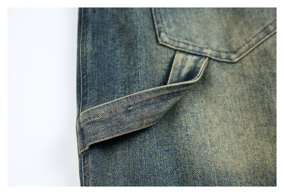 Close-up of blue washed denim with a stitched flap or strap and contrasting tan seams.