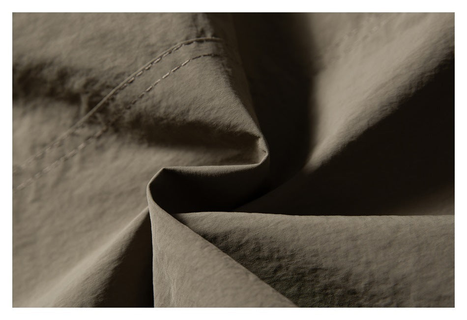 Close-up of a stitched seam and folded taupe garment fabric.