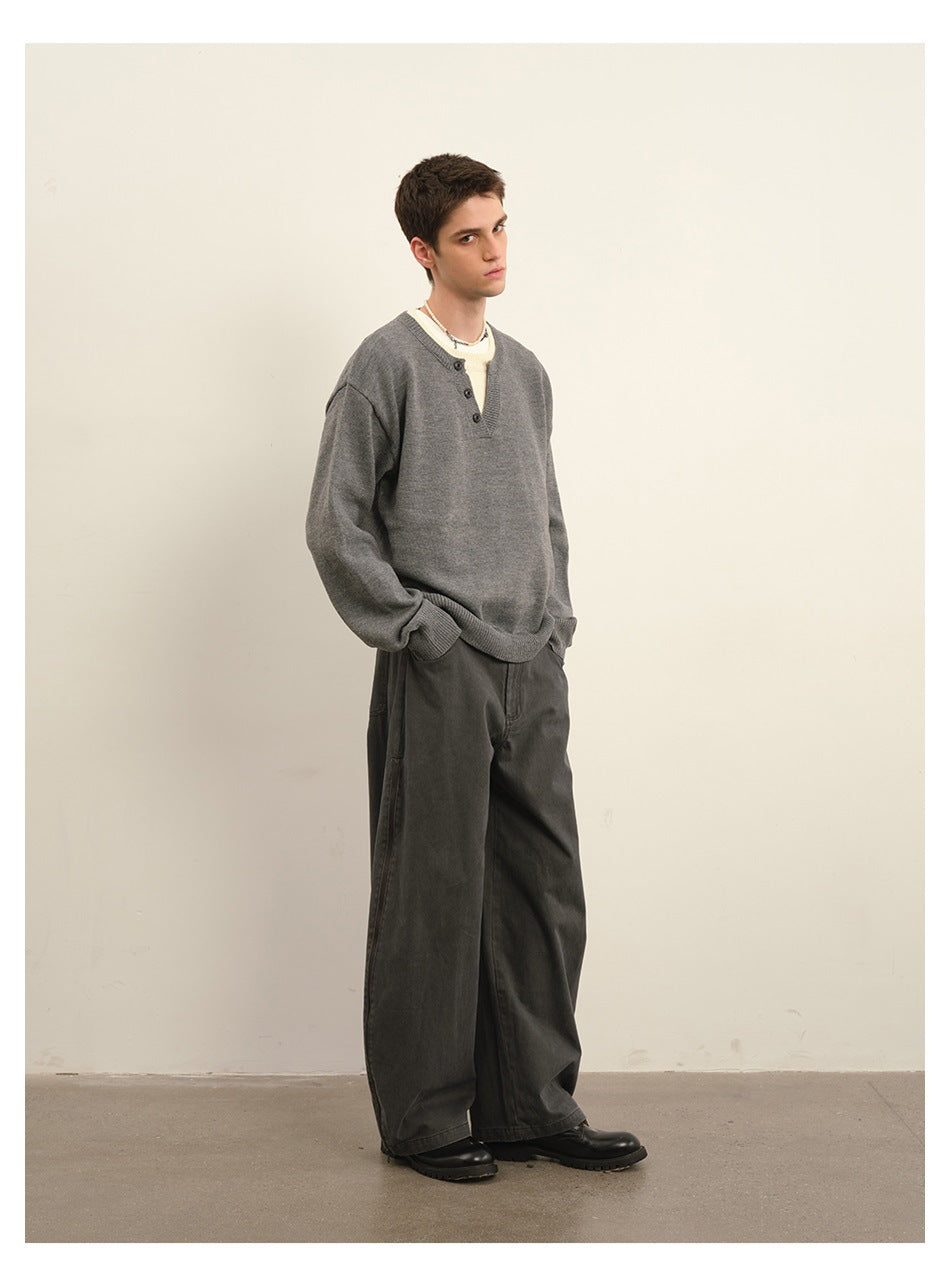 Model wearing a gray button-neck sweater, wide charcoal trousers and black shoes.