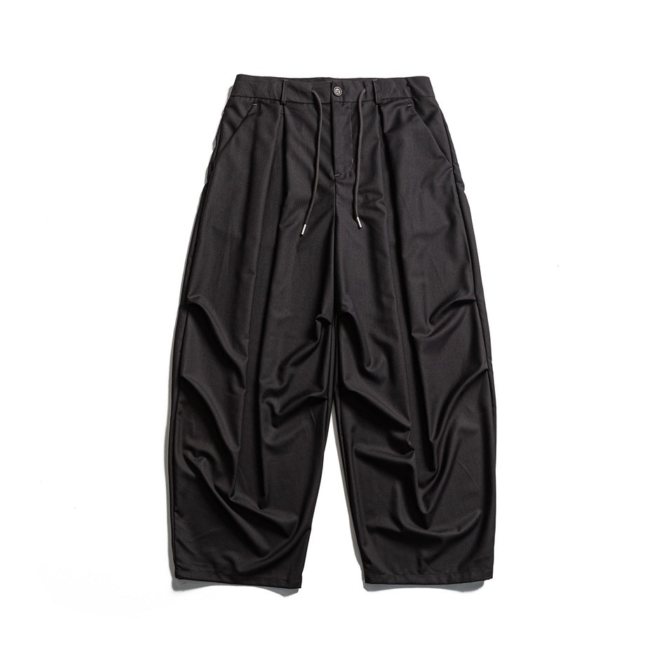 Dark charcoal-black wide-leg pleated trousers with drawstring waist, flat lay front view