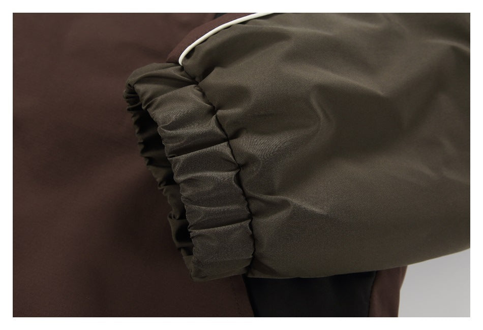Close-up of a jacket sleeve with a dark olive panel, white piping, and gathered cuff.
