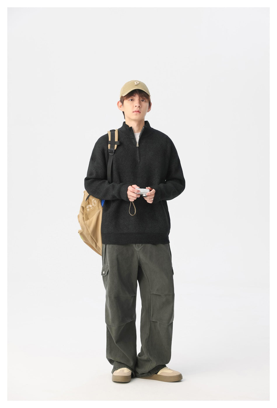 Full-length view of a model wearing a black quarter-zip sweater with loose dark cargo pants.