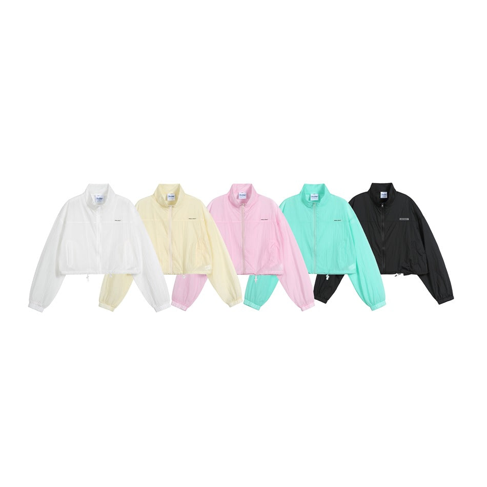 Five cropped zip-up jackets shown together in white, pale yellow, pink, mint, and black.