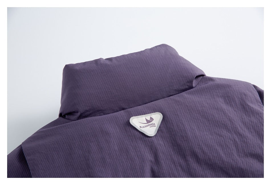 Close-up of a dark purple garment collar and a small triangular BLACKARMADA Outdoors patch.