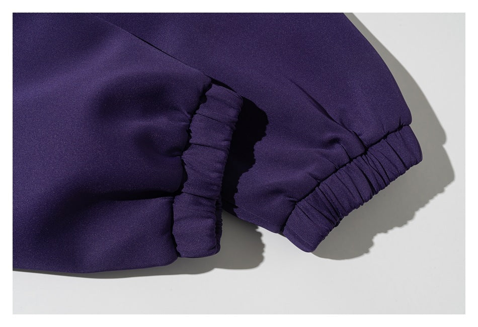 Close-up of a dark purple garment showing a gathered elastic cuff and a folded fabric edge.