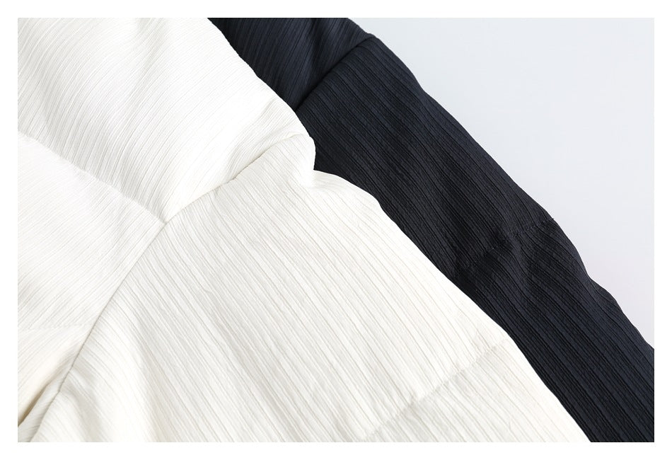 Close-up of ivory and dark navy quilted jacket panels, showing the fine raised linear texture.