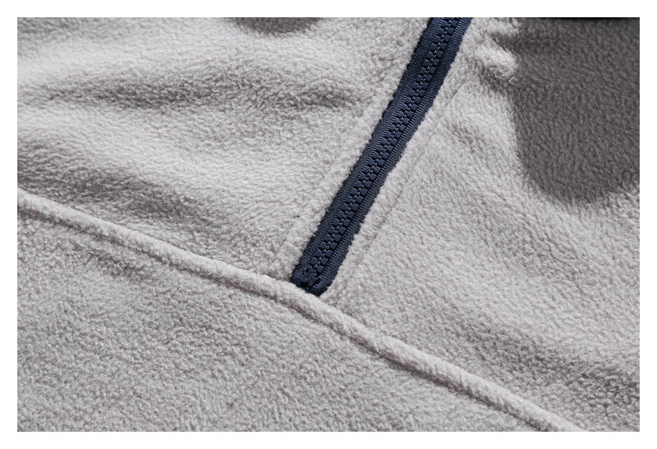Close-up of a dark navy zipper set into light gray fleece fabric.