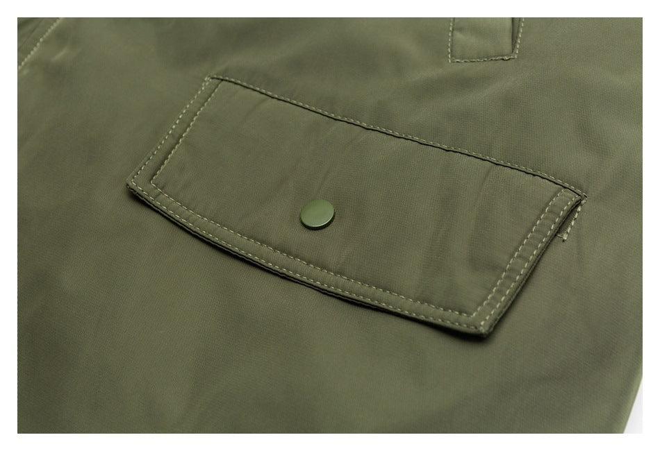 Close-up of an olive jacket's flap pocket with a snap button and contrast stitching.