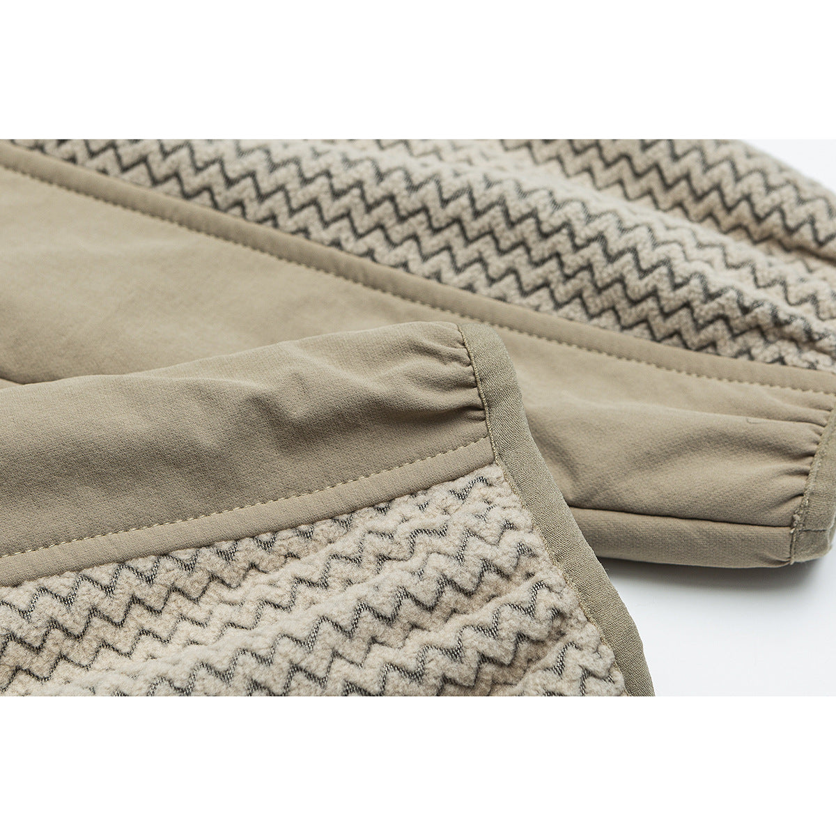 Close-up of a beige sleeve and seam beside cream fabric with a dark zigzag pattern.