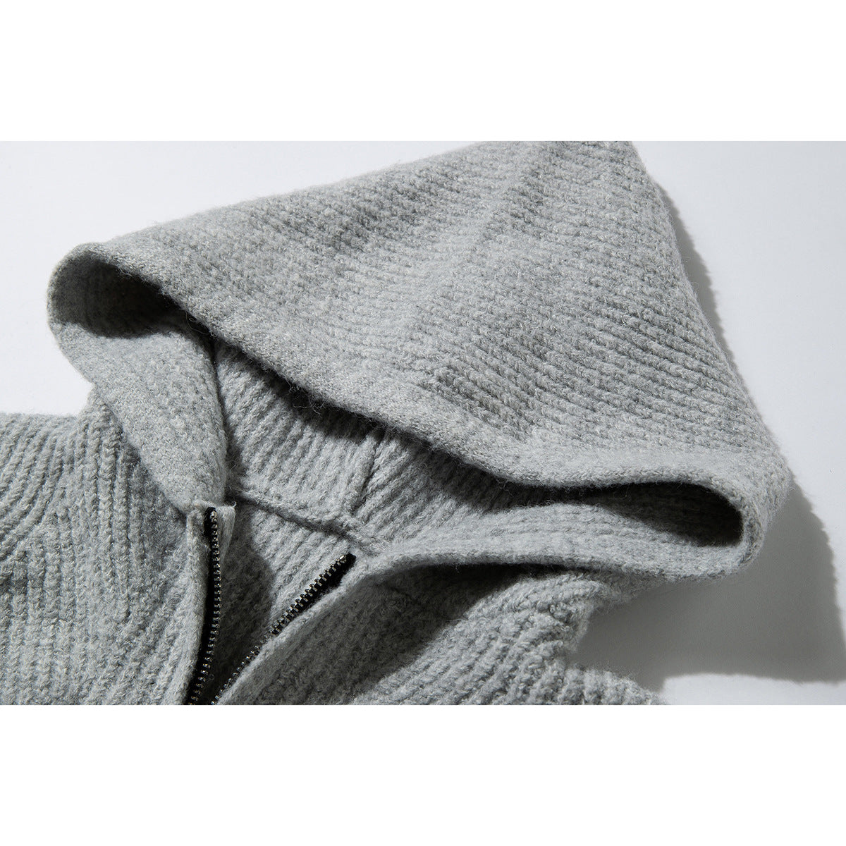 Close-up of a light gray rib-knit hood and short black zipper on a sweater.