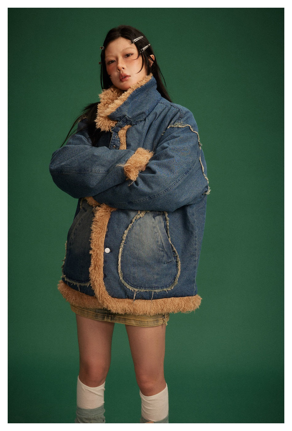 Closer view of a model wearing a blue denim jacket with tan shaggy trim, oversized sleeves, and patch pockets.