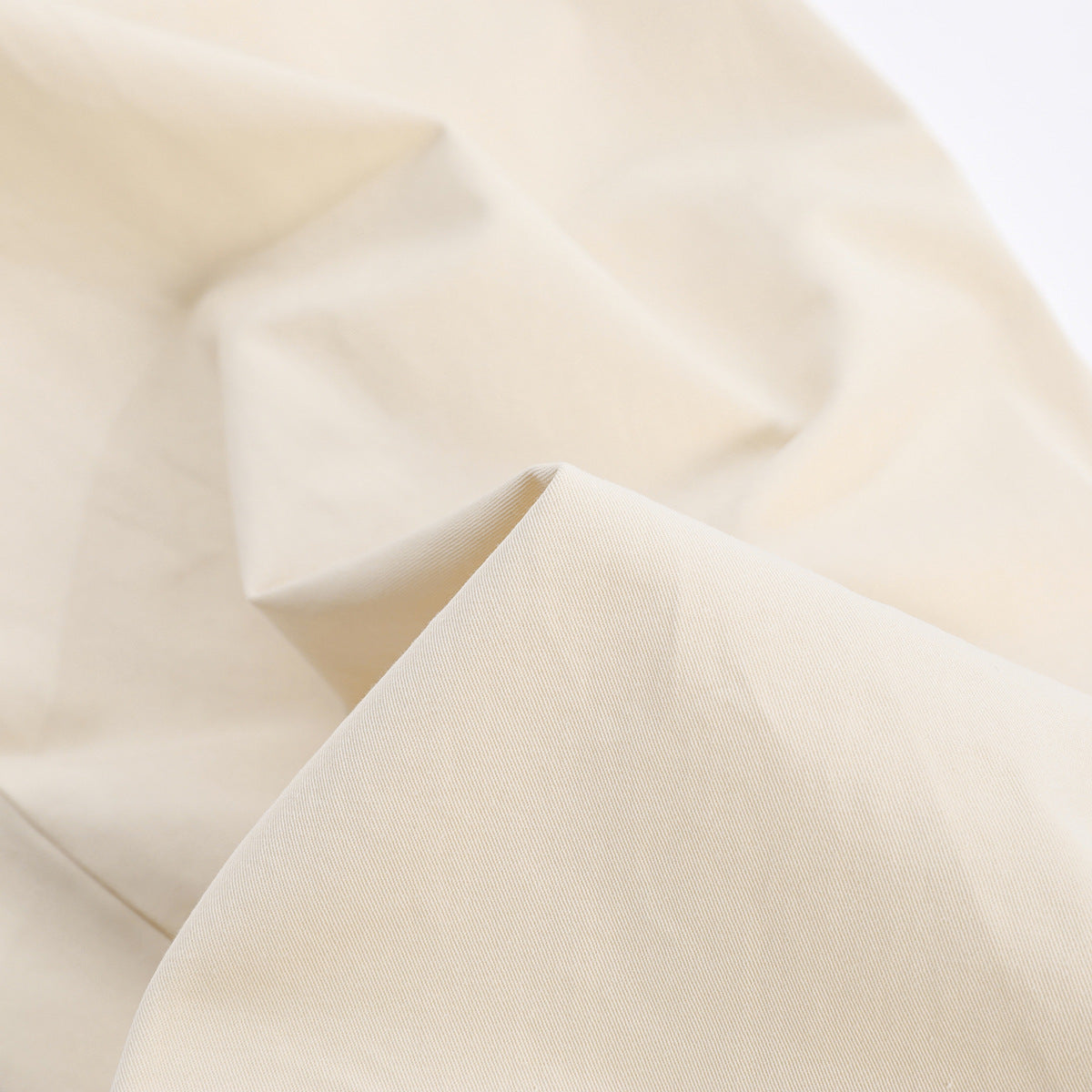 Close-up of the cream fabric, showing its fine diagonal weave and soft folds.