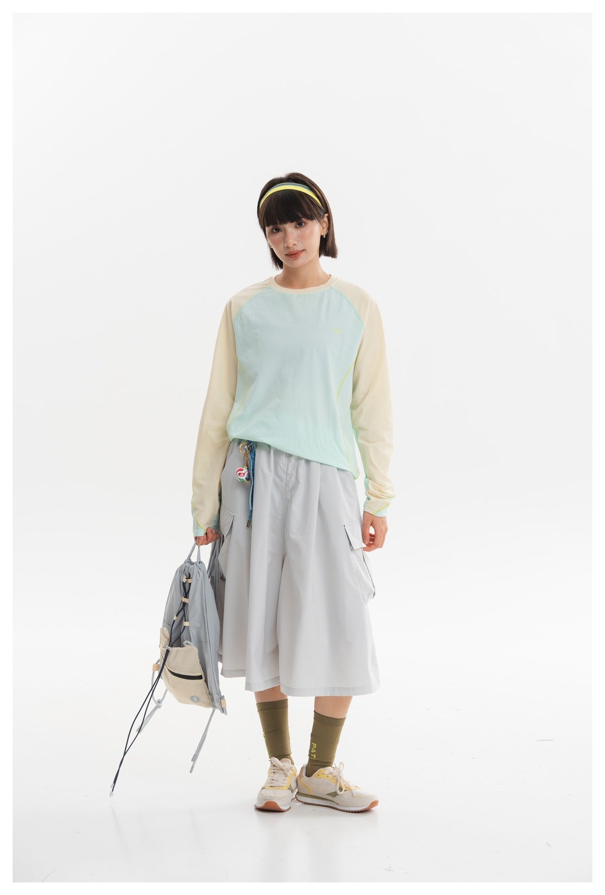 Model wearing a pale aqua raglan long-sleeve top with cream sleeves and a light gray cargo midi skirt, front view.