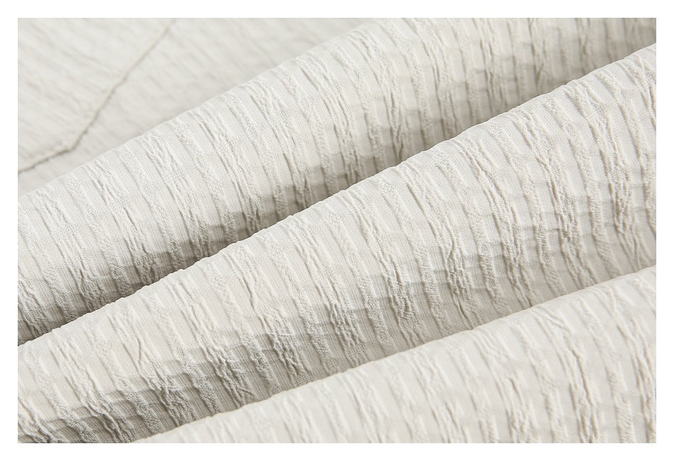Extreme close-up showing the raised, irregular texture of the off-white shorts fabric.