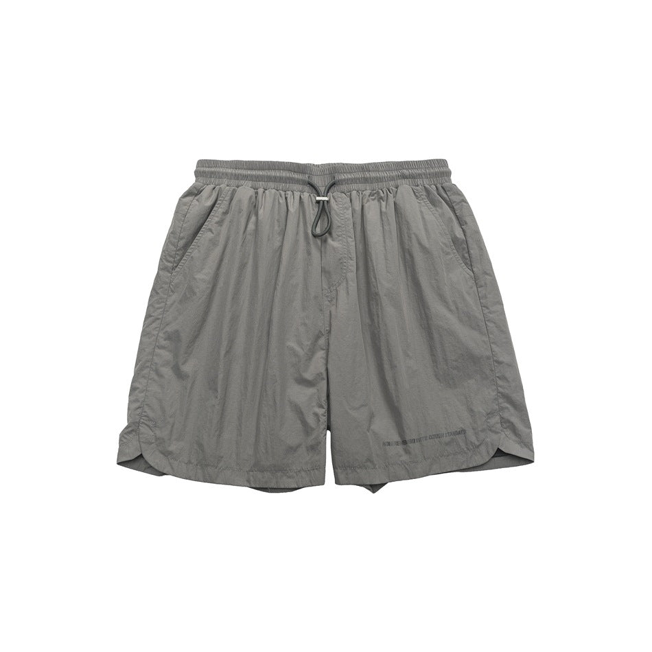 Gray crinkled woven shorts, front view, with elastic drawstring waist, side pockets and curved hem