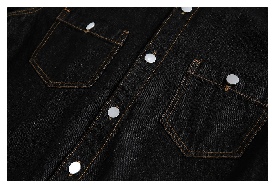 Black denim shirt front detail showing two patch pockets, silver snaps, and orange topstitching.