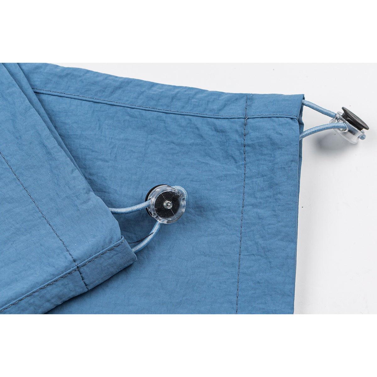 Close-up of blue pants hem with adjustable cord and toggle.