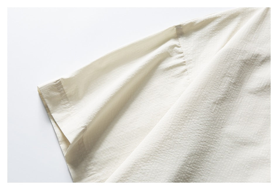 Close-up of the ivory shirt's short sleeve, seam, and textured fabric.