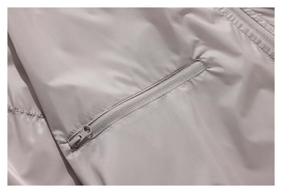 Close-up of a slanted pale zipper pocket on a light taupe jacket.