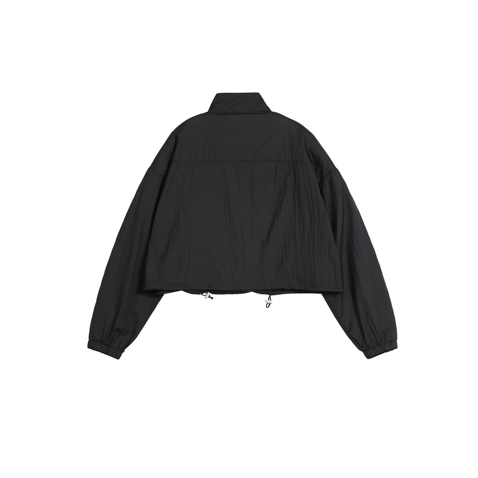 Back view of a black cropped jacket with a high collar, loose long sleeves, elastic cuffs, and adjustable hem cords.
