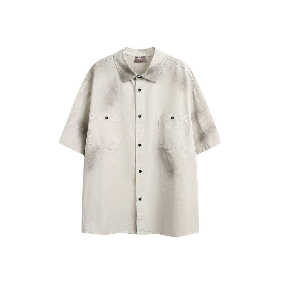 Dirty khaki short-sleeve button-up shirt with two chest flap pockets and gray sprayed distressed marks, front view