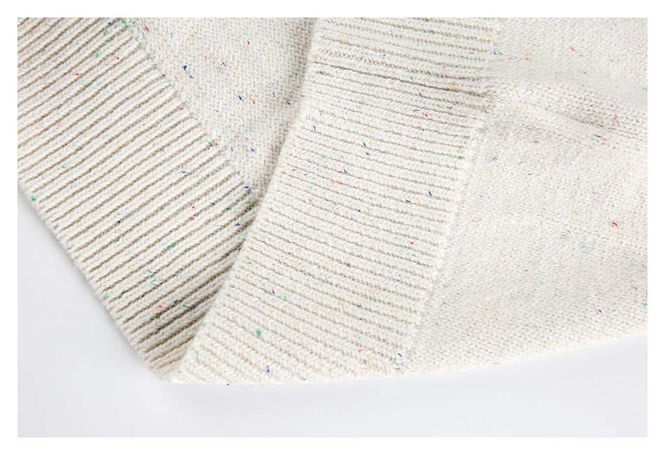 Close-up of cream flecked knit with a wide ribbed edge and folded seam.