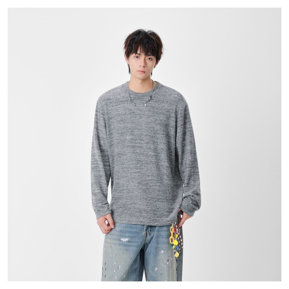 Model wearing gray heathered long-sleeve crew-neck top with chain necklace and distressed light-wash jeans