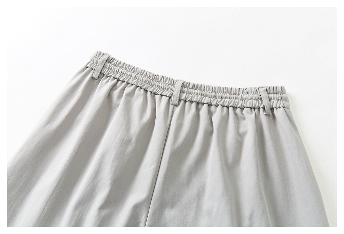 Close-up of the back waist of light gray trousers, showing an elasticated waistband and belt loops.