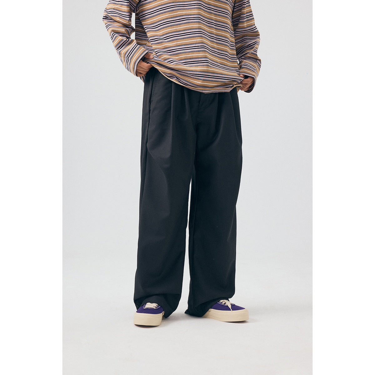 Front view of a model wearing wide-leg black trousers, a tan striped shirt, and purple sneakers.