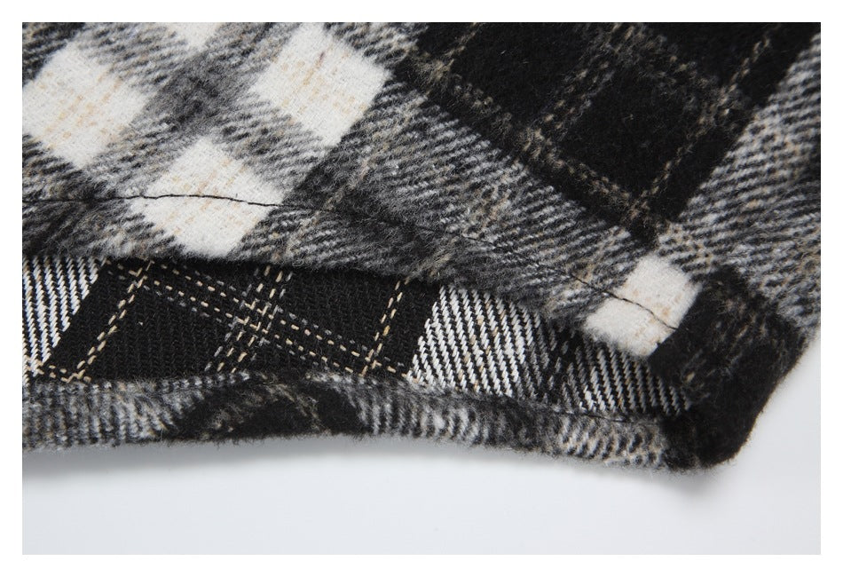 Close-up of a black, gray, and cream plaid garment hem with visible stitching.